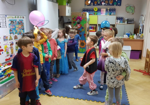Dzieci stojące w dwóch rzędach w sali przedszkolnej.